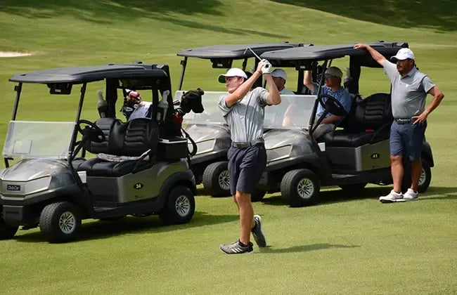 young male golfer teeing off second golfer watching